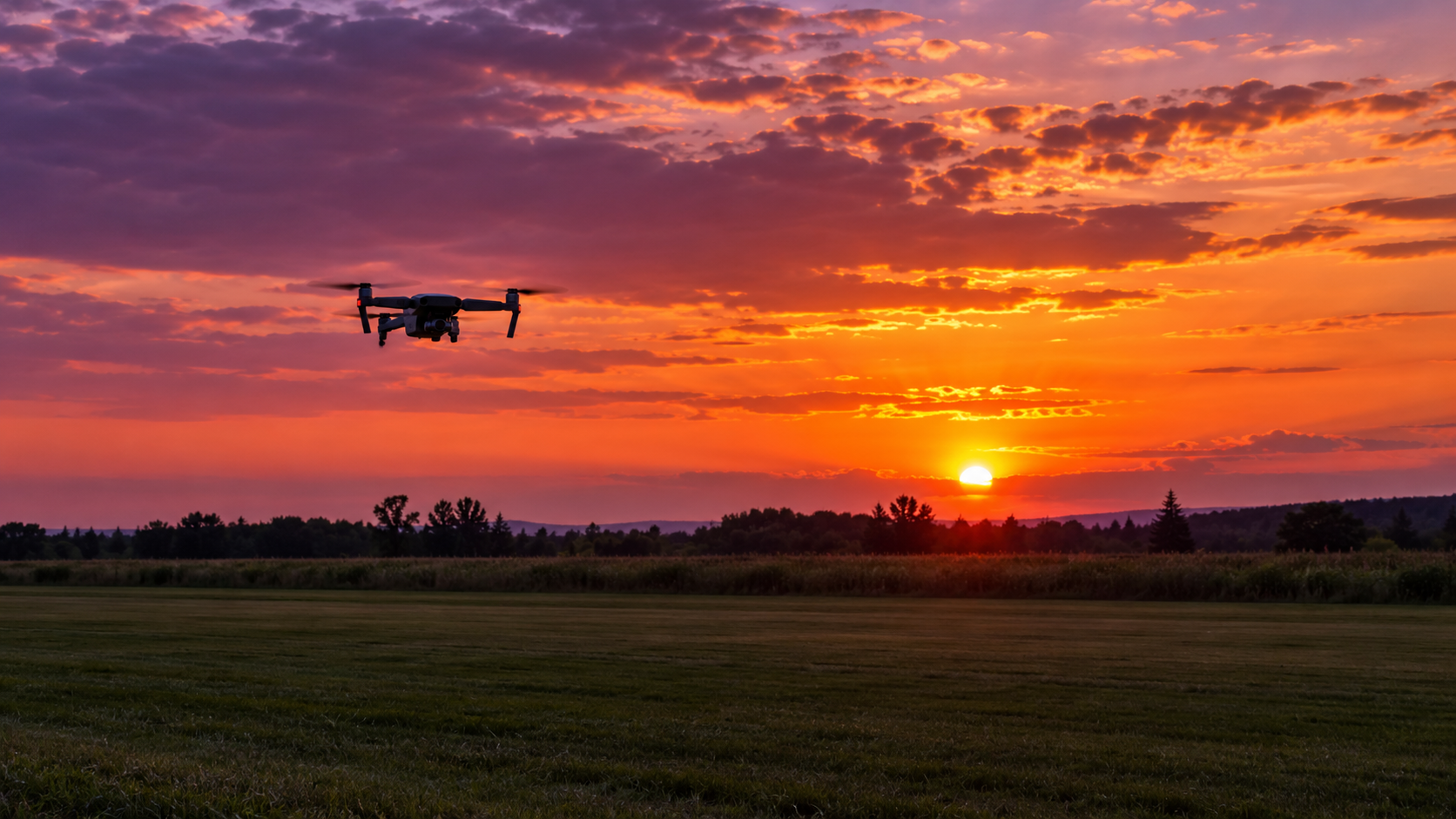 Small drone flying against an orange sunset at the club field