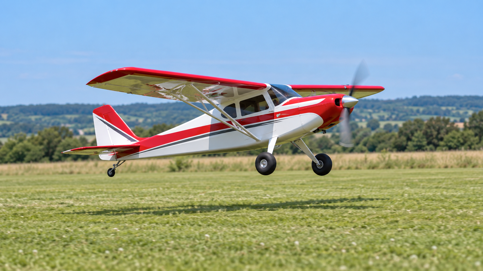 Red and white RC plane taking off over grass