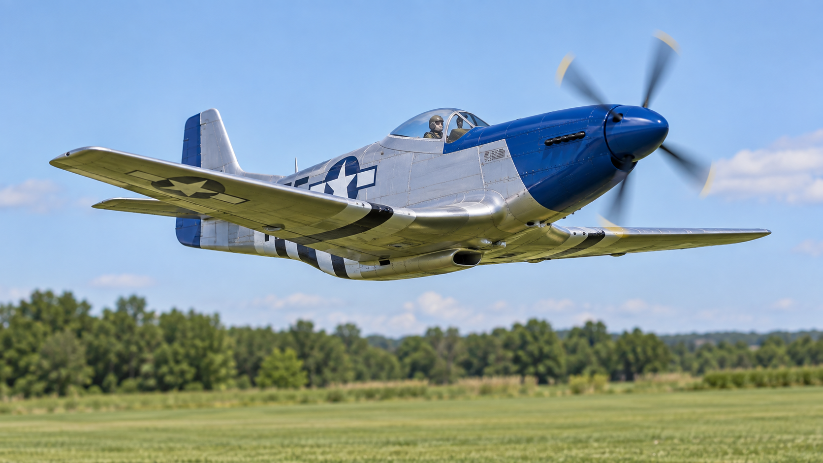 Silver and blue model warbird flying above the club field